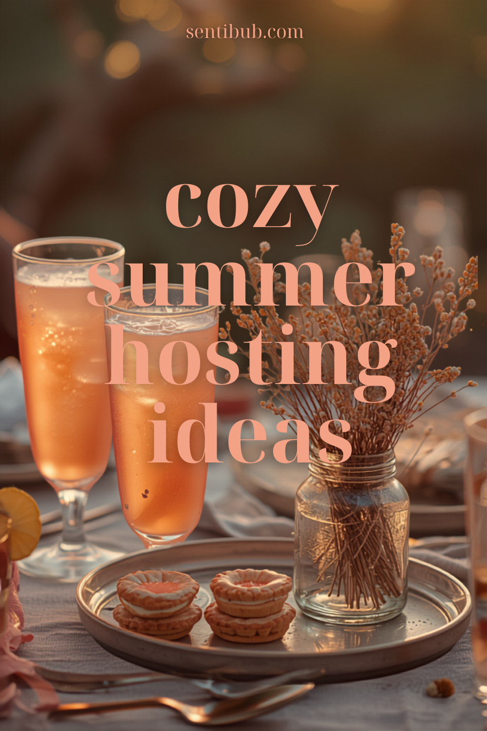 cozy summer hosting — golden hour backyard table with pink lemonade in glasses, mini desserts on a tray, and wildflowers in a mason jar